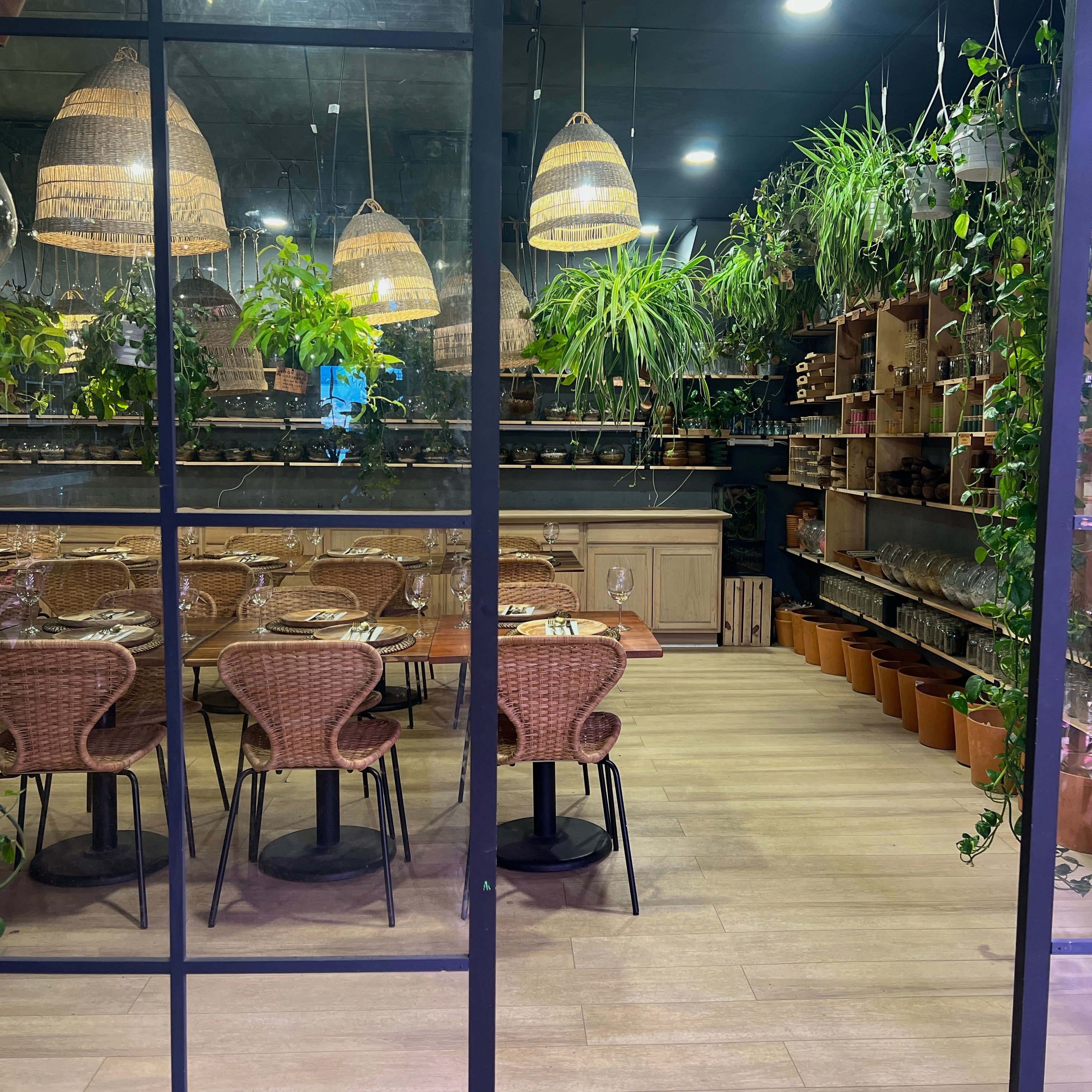 the private event room at spotted leaf plant company seen through the glass wall, tables set under woven pendant lights