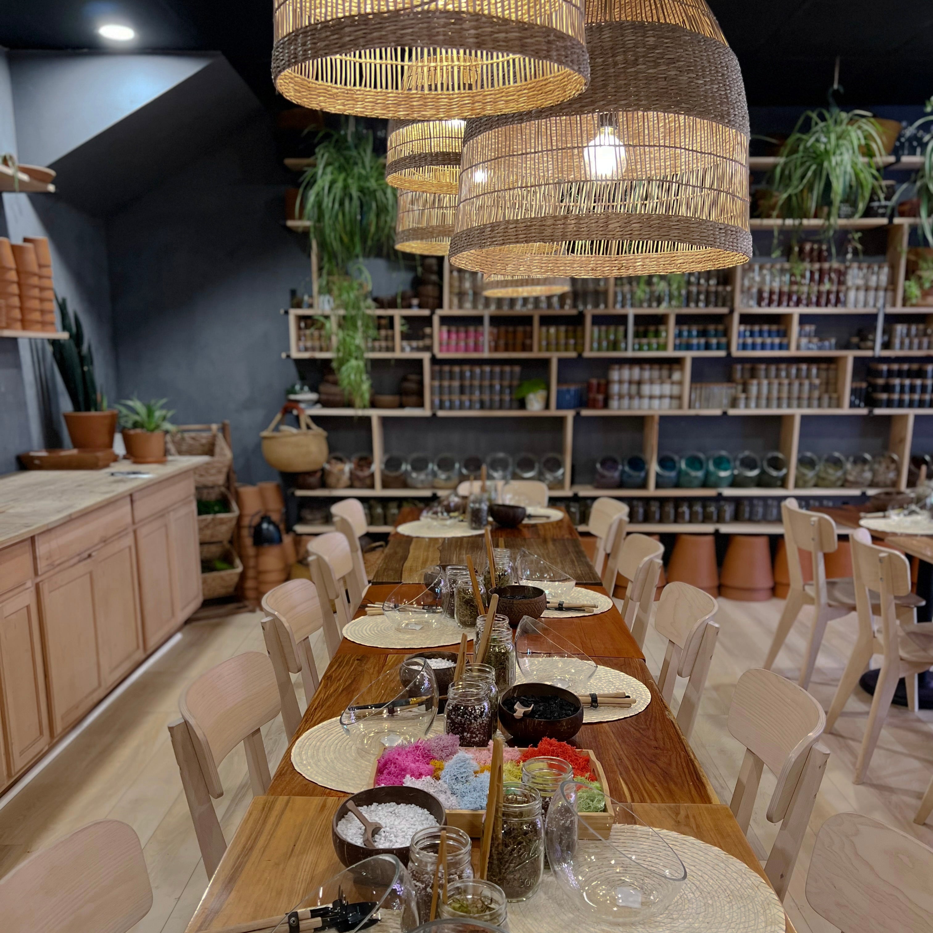 the private event room at spotted leaf set for a terrarium class, long wooden tables with tools and supplies at each seat